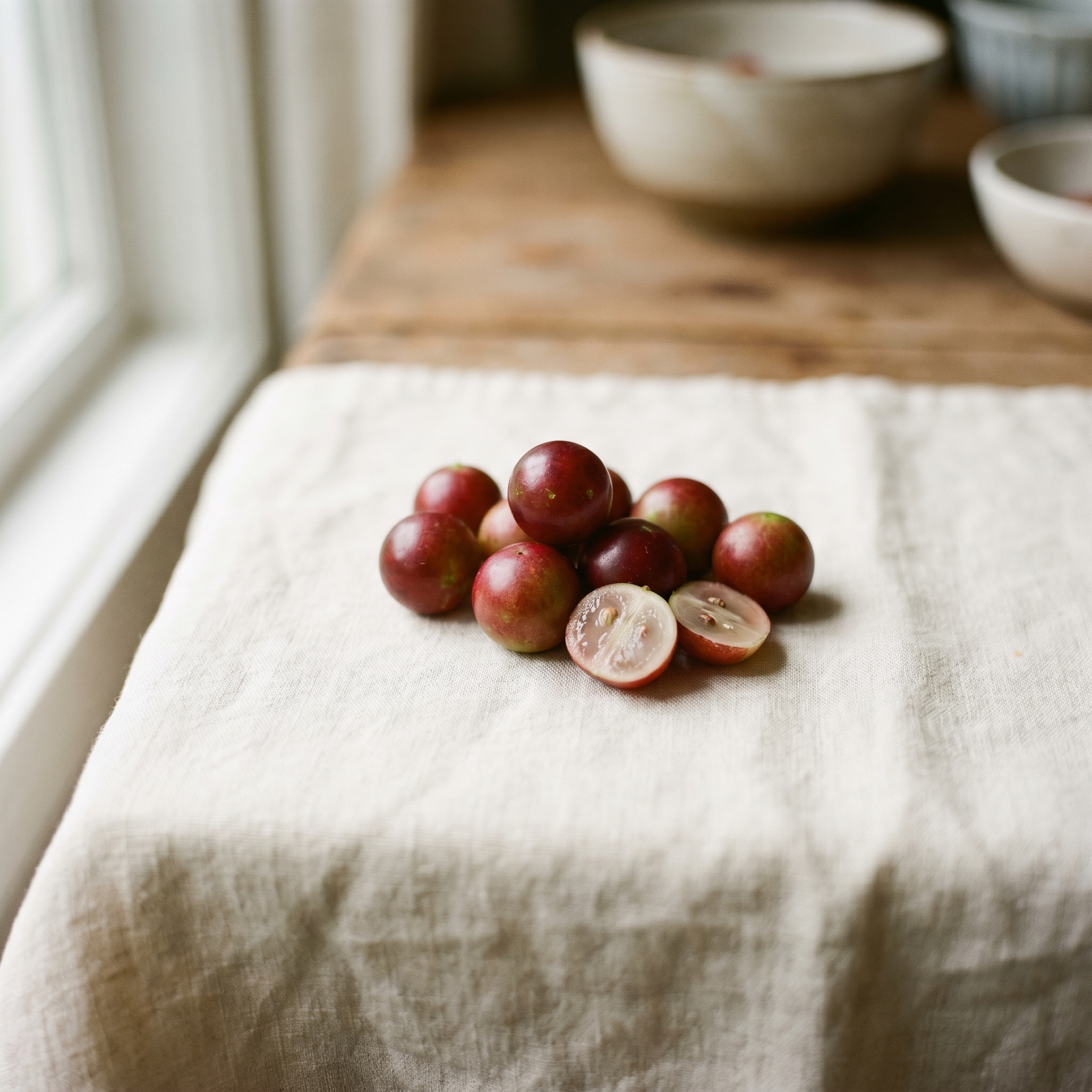 Camu camu, a small reddish-purple Amazonian berry, one halved showing pale flesh.
