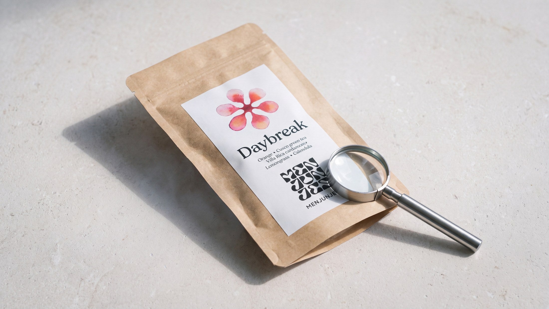 A Menjunjes Daybreak tea pouch examined with a loupe on a pale stone surface