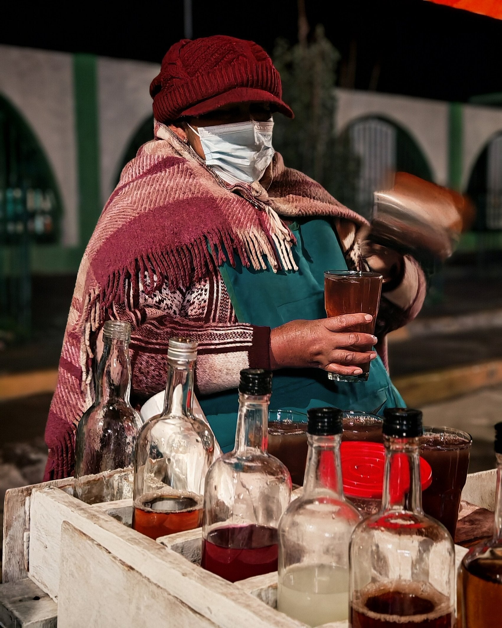 An emoliente vendor pouring the hot brew between vessels in Peru