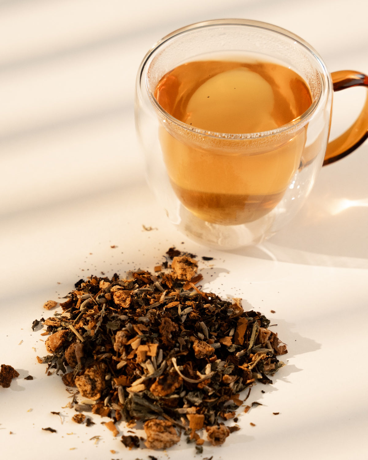 Dusk brewed in a clear double-wall glass cup beside the loose blend