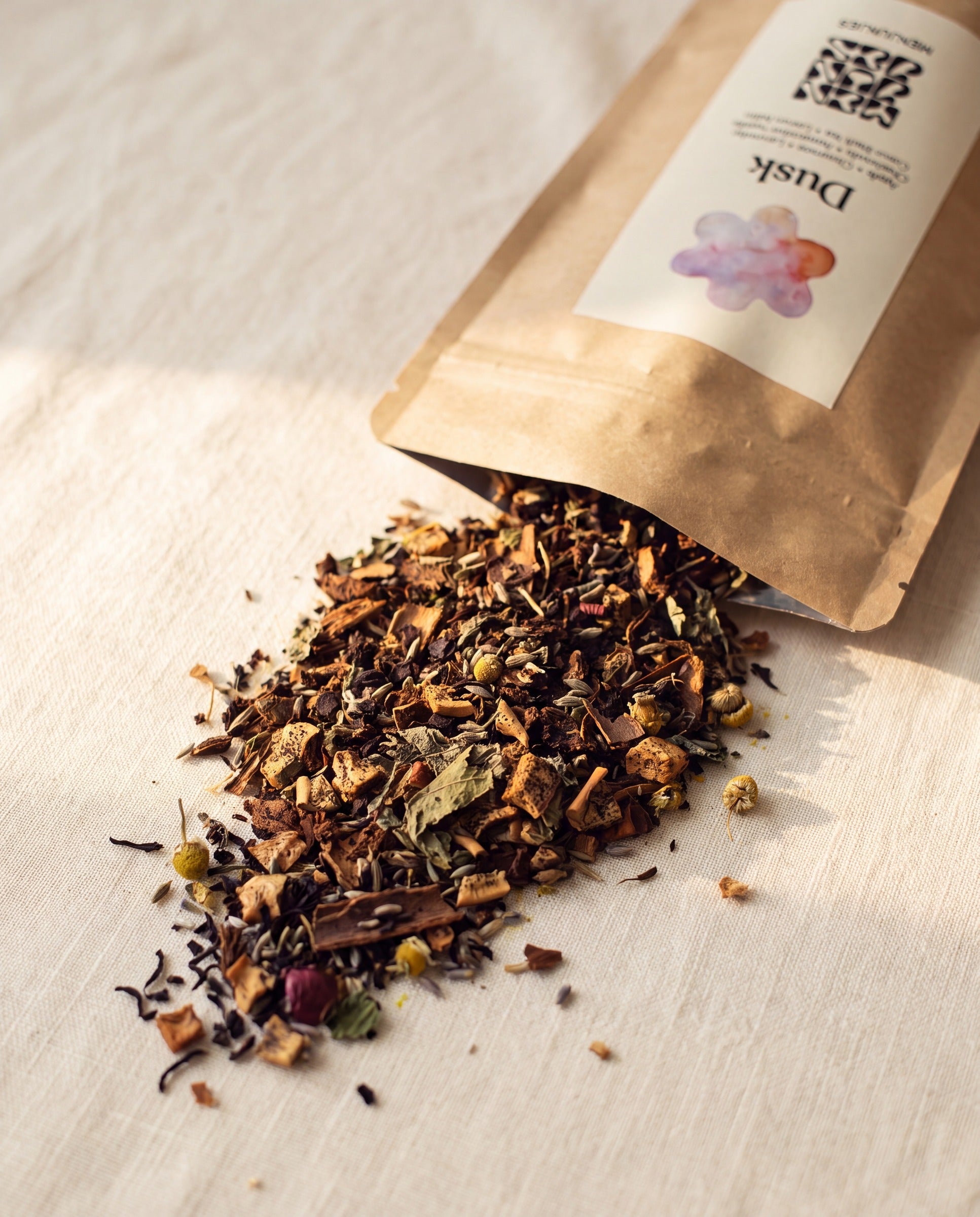 Menjunjes Dusk pouch with loose-leaf tea spilling onto cream linen